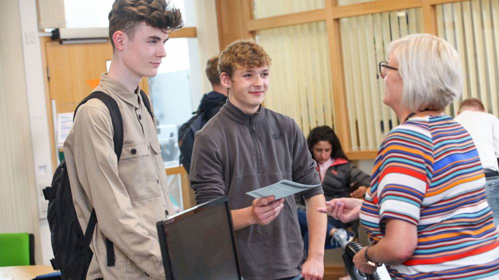 Dysgwyr yn cael cymorth gan aelod o staff
